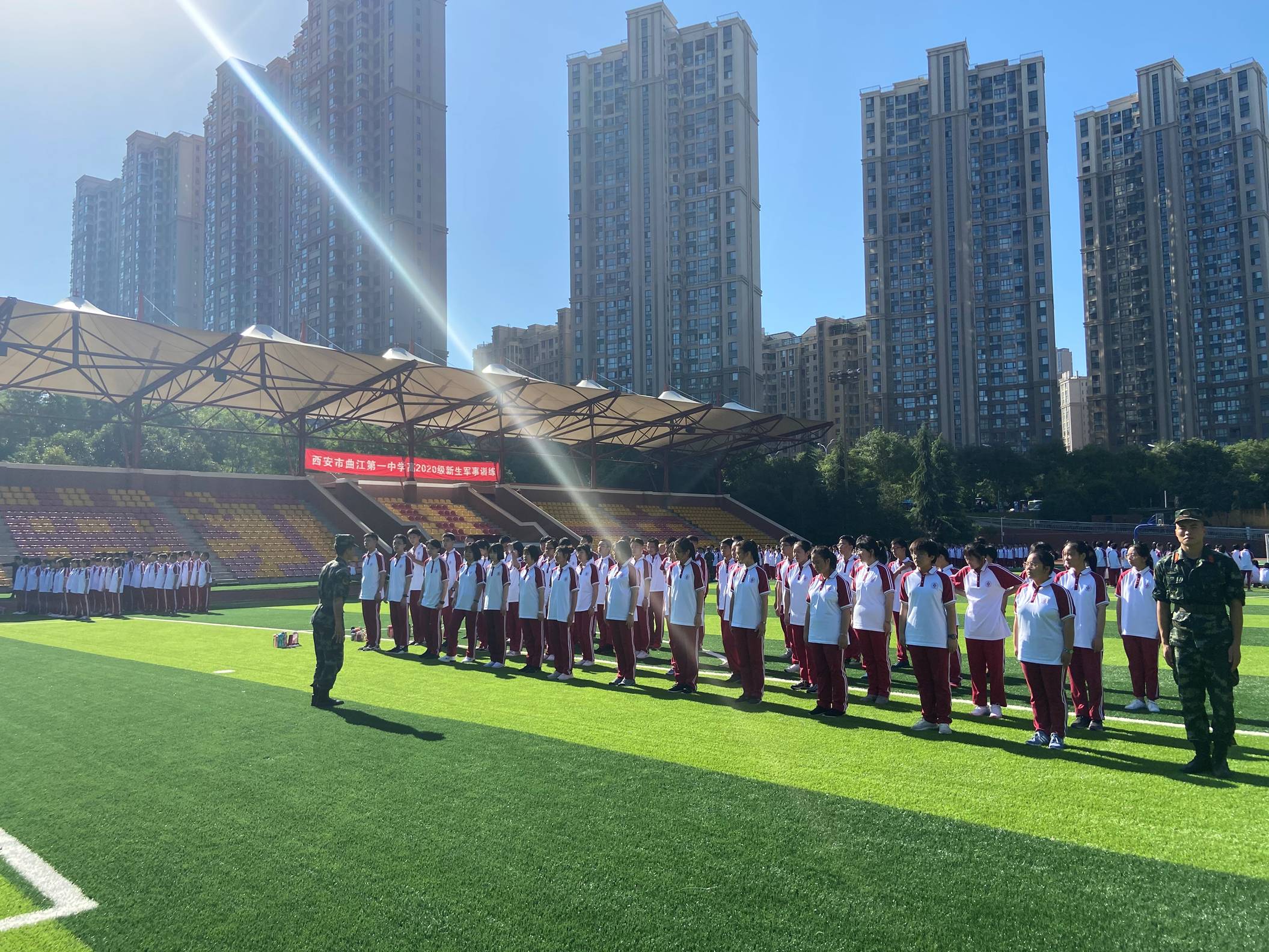 金色光芒,绿茵之上,身着曲江红的高2020级新生表情刚毅、布列整齐.jpg